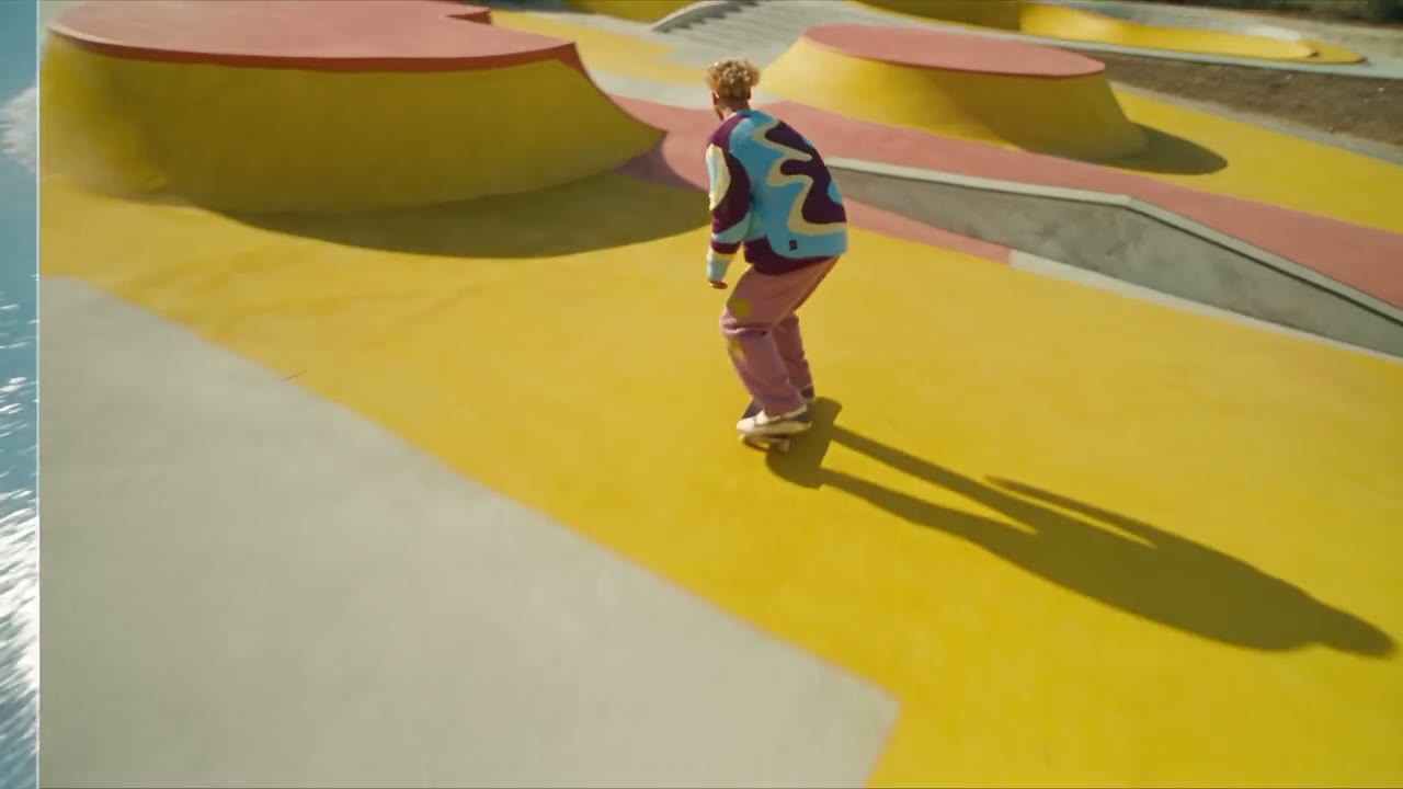 A skateboarder mid-air as an alpine snow field becomes a pastel yellow skate bowl